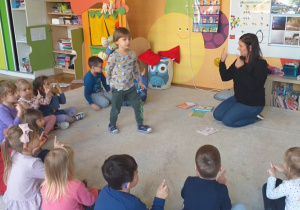 Na zdjęciu widać grupę dzieci z ciocią uczące się języka migowego.
